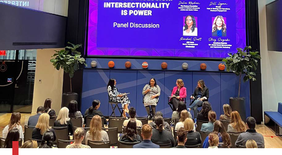 four women leading discussion on panel in front of crowd